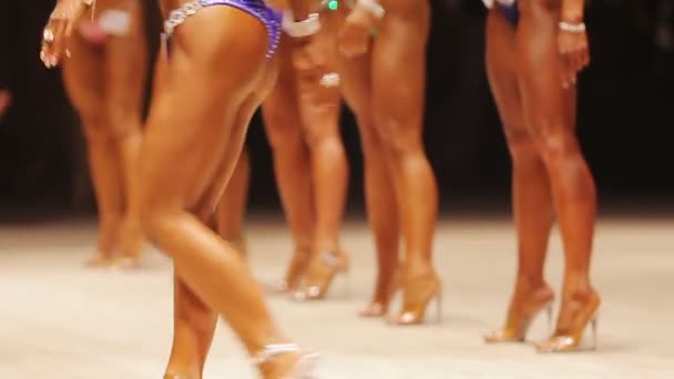 Kvinnor med vackra garvade fit kroppar promenader på scenen, fitness tävling — Stockvideo