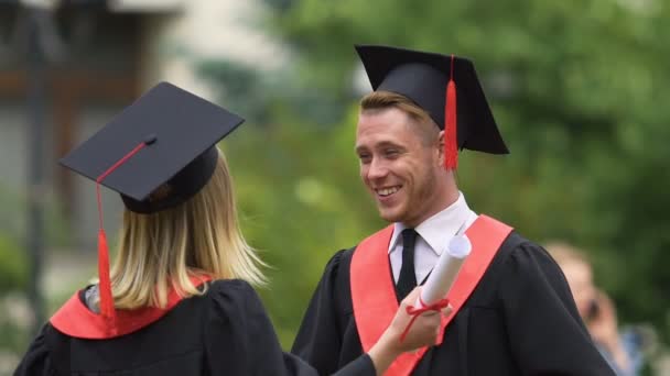 Estudiantes felices intercambiando felicitaciones, abrazándose calurosamente, ceremonia de graduación — Vídeo de stock