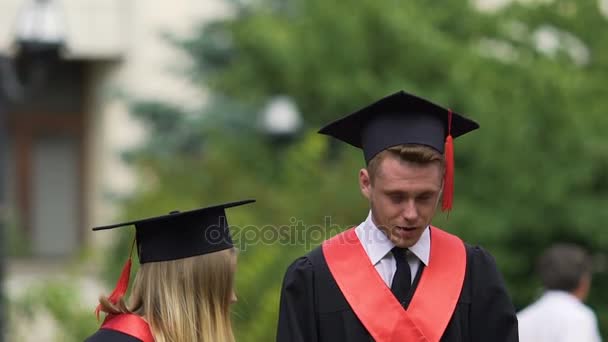Смешной выпускник делает кричащее лицо, держа в руках дипломы университета — стоковое видео