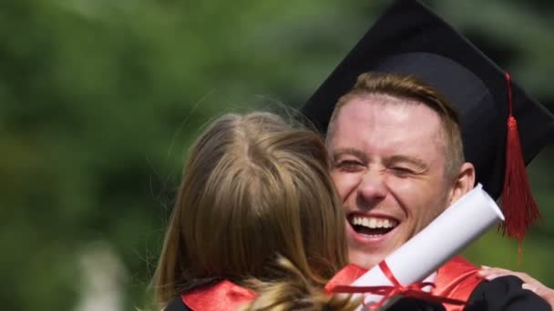 Amigos de la universidad de buen humor riendo y abrazándose después de la ceremonia de graduación — Vídeos de Stock