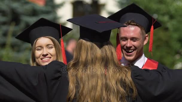 Amigos de la universidad abrazándose calurosamente, felicitaciones por la graduación exitosa — Vídeo de stock
