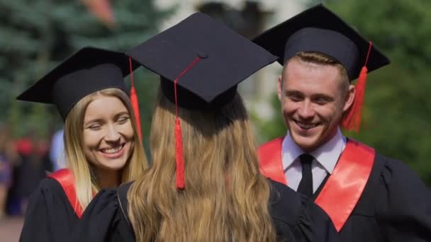 Lento-mo de graduados felices intercambiando felicitaciones, amigos abrazándose calurosamente — Vídeos de Stock