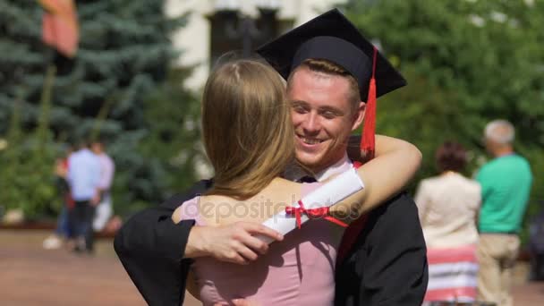 Hermosa mujer felicitando novio en la graduación, feliz pareja abrazo — Vídeos de Stock