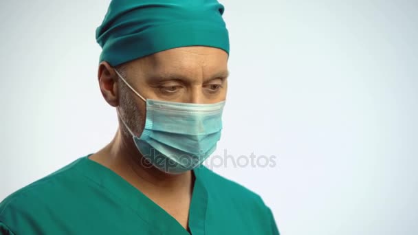 Medico in maschera facciale annuisce e prende la siringa, preparandosi a fare l'iniezione — Video Stock