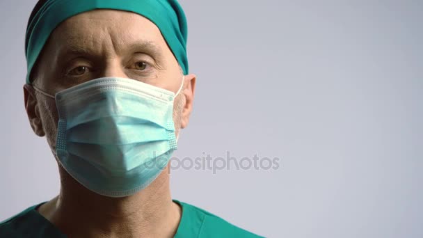 Σοβαρό πρόσωπο του χειρουργού στην ιατρική μάσκα ψάχνει για φωτογραφική μηχανή, ασφάλιση υγείας — Αρχείο Βίντεο
