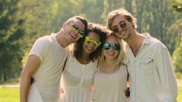 Sinceros sorrisos em rostos de homens e mulheres jovens abraçando e posando para câmera — Vídeo de Stock