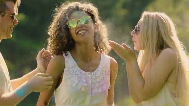 Glada unga män och kvinnor blåser färg pulver från händer, ger hög fem — Stockvideo