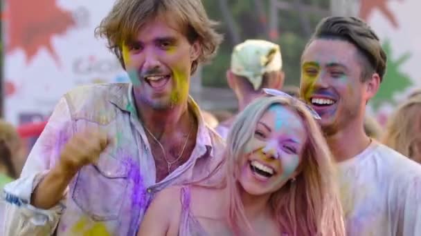 Dronken jonge vrienden bedekt met kleurrijke verf uitvoeren gek dans op festival — Stockvideo