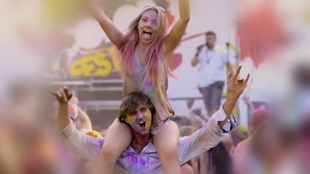 Ellerini sallayarak açık konserde adamın omuzlarında oturan mutlu genç kadın — Stok video