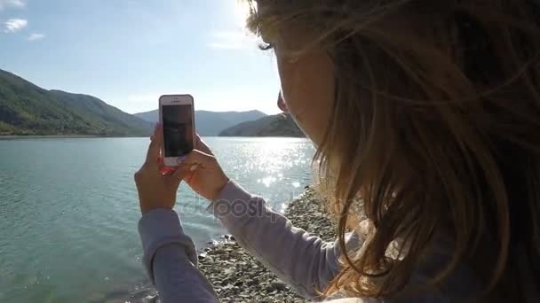 Frau filmt an einem sonnigen Tag Berglandschaft und Fluss mit dem Handy — Stockvideo