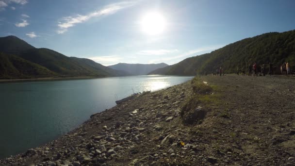 Klarer, sonniger Tag und sonniger Fluss in den Bergen, Gruppe von Menschen am Flussufer — Stockvideo