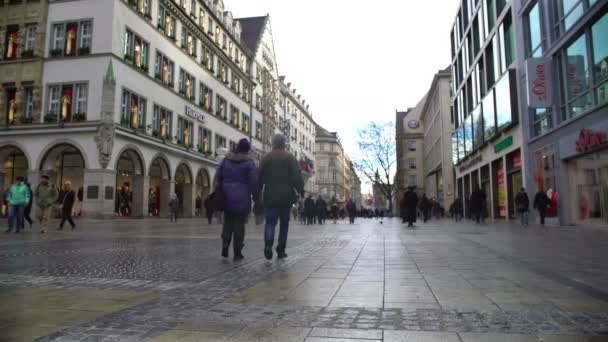 MUNICH, ALEMANIA - CIRCA ENERO 2016: Turistas en un tour turístico. Gente caminando por la plaza St. Mary con muchas tiendas en Munich, de compras — Vídeo de stock