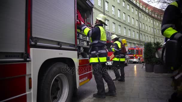 MUNICH, ALEMANIA - CIRCA ENERO 2016: Bomberos alemanes trabajando. Bombero poniendo equipo en camión de bomberos, trabajo peligroso, responsabilidades — Vídeo de stock
