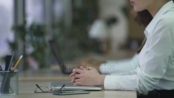 Kvinna sitter vid skrivbord med händerna vikas på laptop, business dag början — Stockvideo