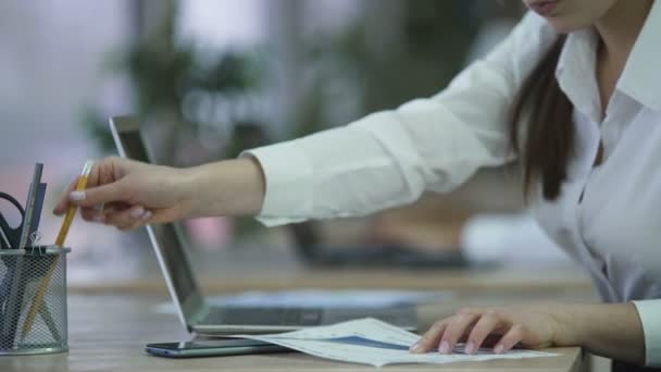 Femme insérant des données sur ordinateur portable à partir de documents papier, préparer un rapport au bureau — Video