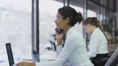 Ofiste oturan ve arkadaşıyla telefonda konuşurken güzel karışık yarış Bayan