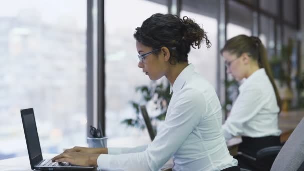 Carrera mixta mujer de negocios tomando notas, escribiendo en el ordenador portátil, gerente trabajador — Vídeo de stock