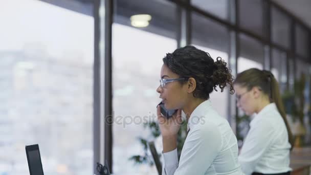 Travailleuse souriante et joyeuse parlant sur smartphone avec le client, travail d'équipe — Video