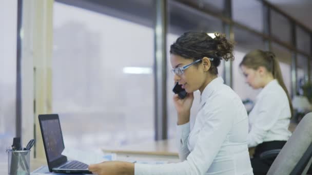 Mujer de negocios hablando por teléfono celular y trabajando en el proyecto, ambiente de oficina — Vídeos de Stock