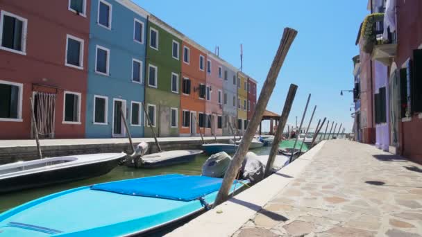 Canal de l'île de Burano avec des bateaux à moteur amarrés le long de la rue avec des bâtiments colorés — Video