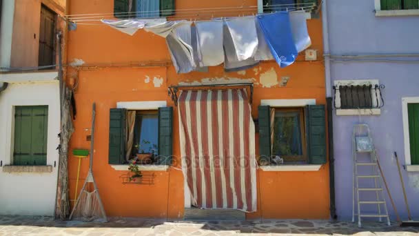 Шейббі фасад старого помаранчевого будинку з сушеним пранням та рибальським обладнанням — стокове відео