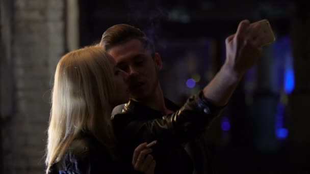 П'яний хлопець знімає на смартфоні свій поцілунок з дівчиною на вечірці, погані звички — стокове відео