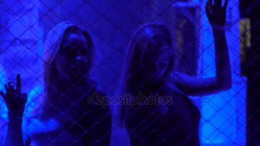 Disko, gece hayatı, metal zincir çit arkasında dans iki güzel kız