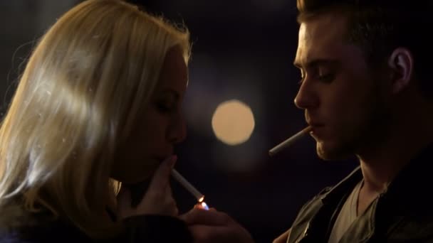 Hombre joven encendiendo el cigarrillo de mujer en el club nocturno, pareja borracha besando — Vídeos de Stock