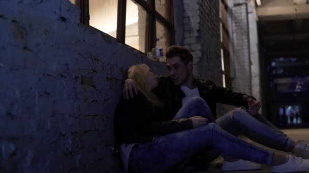 Casal bêbado sentado no chão perto da parede e falando, vida noturna, hook-up — Vídeo de Stock