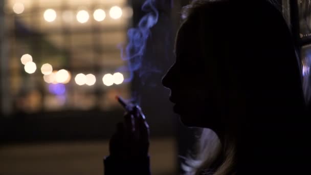 Weibliche Silhouette, die auf der Straße steht und Zigarette raucht, melancholisch — Stockvideo