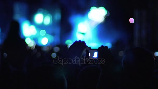 Руки человека, держащего смартфон в воздухе, чтобы снять видео концертной атмосферы — стоковое видео