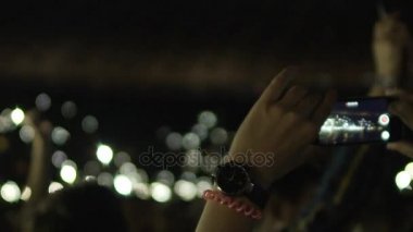 Eller genç kadının ışıkları ile gadget kalabalığın üzerine karanlıkta filme