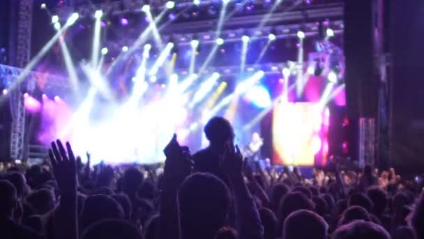 Az izgatott közönség a koncerten kezet emelt a levegőben, ugrás árnyékok lassú mo — Stock videók