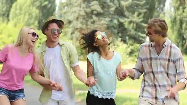 Orang-orang muda yang gembira tertawa, menari dan melompat tinggi sambil memegang tangan — Stok Video