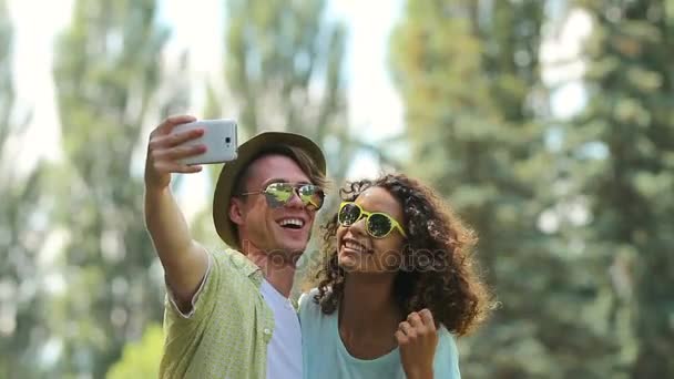 Novio y novia sonriendo brillantemente a la cámara, tomando fotos de sí mismos — Vídeos de Stock