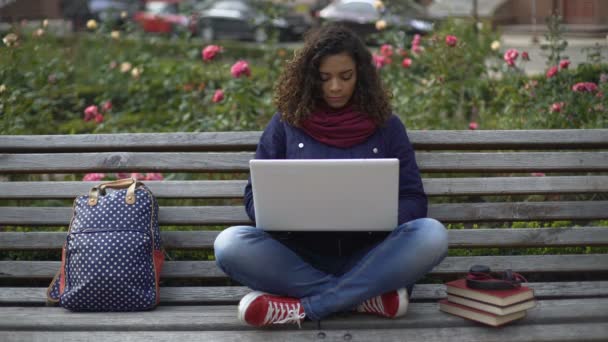 Joven estudiante sentada en el banco al aire libre totalmente absorta en el estudio — Vídeos de Stock