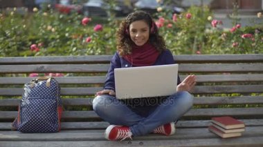 Kamera için poz ve gülümseyen Kulaklığımda sevimli çok ırklı kıvırcık saçlı kız