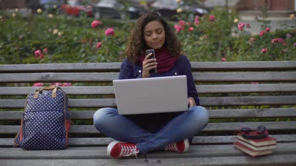 Молодая красивая женщина отдыхает на скамейке в парке, делает телефонный звонок другу — стоковое видео