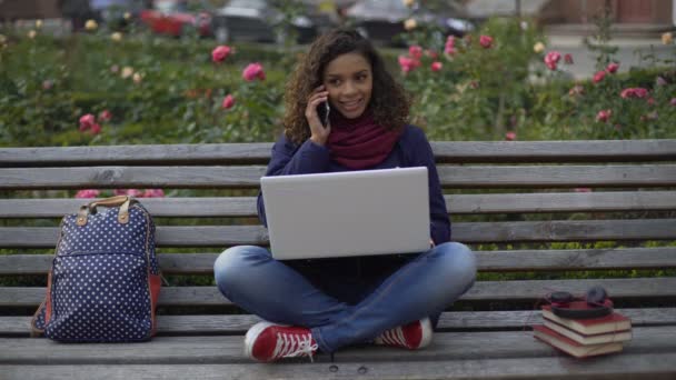 Enthousiast vrouwtje communiceren met vriendje op de telefoon, studeren op Bank — Stockvideo