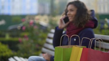 Telefon üzerinden arkadaşlarına yeni satınalmalar hakkında övünme mutlu biracial kadın