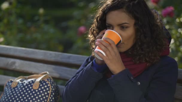 Привлекательная женщина смешанной расы разговаривает по телефону и пьет кофе на открытом воздухе — стоковое видео