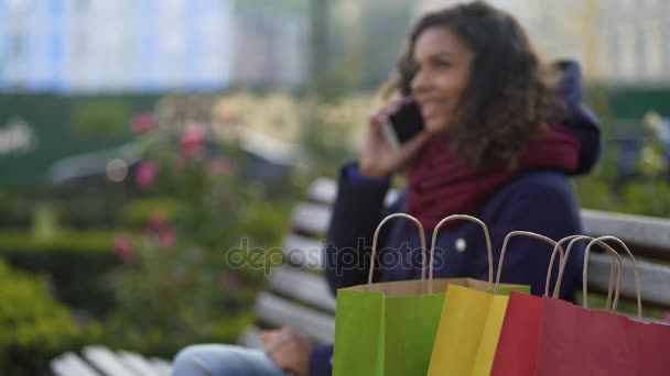 Lycklig biracial kvinna skryter om nya inköp till hennes vänner över telefon — Stockvideo