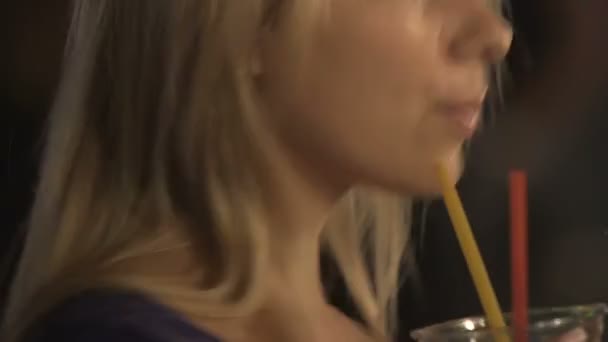 Attractive young female drinking a cocktail, flirting and smiling at nightclub