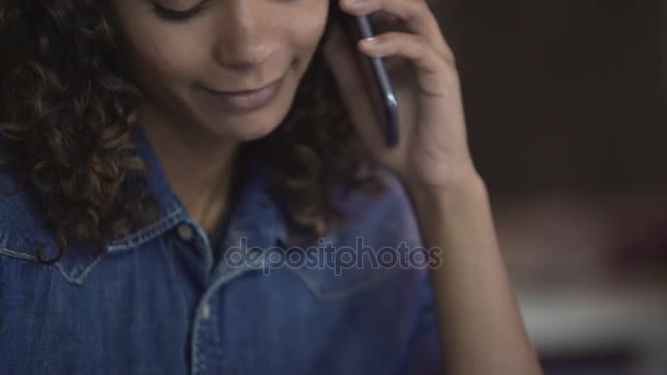 Hermosa mujer birracial rizado hablando en el teléfono inteligente y sonriendo, emociones — Vídeo de stock