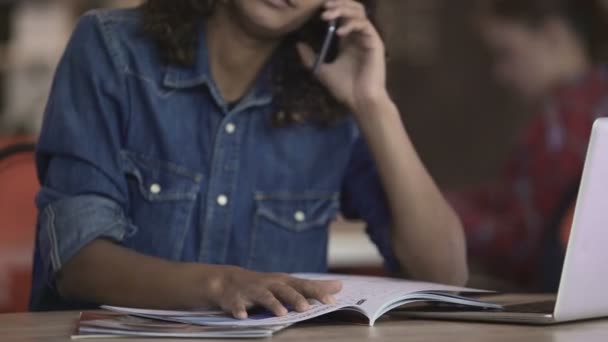 Gelukkig biracial dame praten aan de telefoon en bekijken van foto's in tijdschrift — Stockvideo