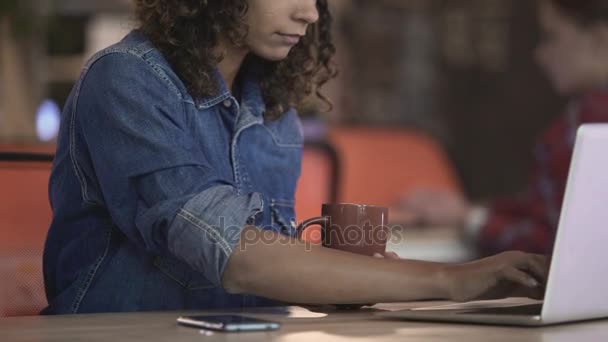 Joyeux jeune femme boire du thé et bavarder avec un ami sur un ordinateur portable, gadgets — Video