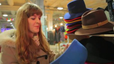 Kadın müşteri mağazada eğleniyor, şirin komik şapka koyarak