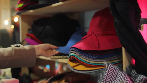 Mujer joven eligiendo sombreros de gran surtido estacional en los grandes almacenes — Vídeos de Stock