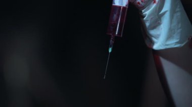 Şırıngadan, düşen kan damlaları yakın çekim elleri kanlı eldivenler