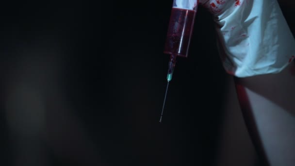 Gotas de sangue que caem da seringa, perto de mãos que usam luvas sangrentas — Vídeo de Stock